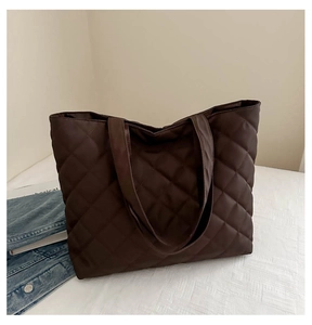 Close-up of a large dark brown quilted tote bag with diamond stitching and dual handles