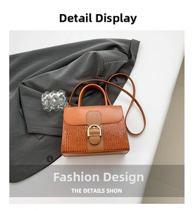 Détail du sac en cuir marron avec texture crocodile et boucle dorée en forme de D