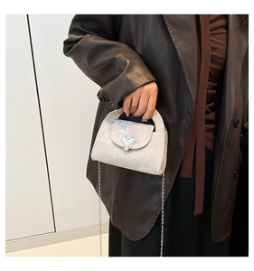 Detail of silver heart buckle mini bag with metallic chain strap on model