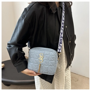 Détail du sac bandoulière matelassé bleu clair avec gland doré et sangle texturée