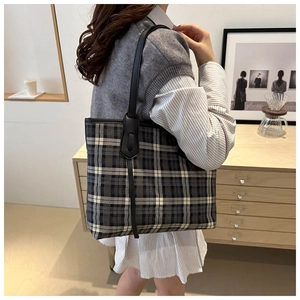 Detail view of large checkered tote bag showing black and white pattern on a female model