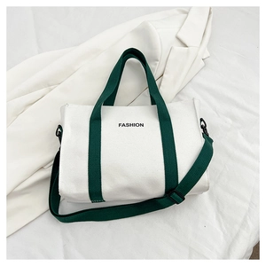 Detail view of canvas tote bag with contrast green handles and black fashion lettering