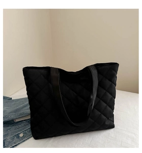 Detail of black quilted tote bag showing padded rhombus stitching and soft nylon texture