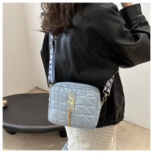 Détail du sac à bandoulière matelassé bleu clair avec logo SS doré et pompon