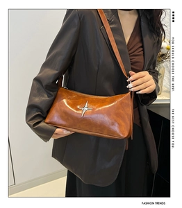 Close-up of retro brown glossy leather pillow bag with silver four-point star hardware