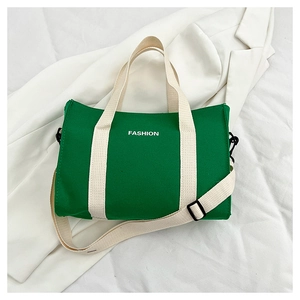Detailed top view of a green canvas tote bag featuring contrast straps and fashion lettering