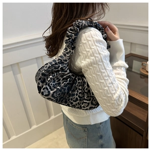Détail du sac nuage froncé à motif léopard gris porté à l'épaule sur un pull blanc