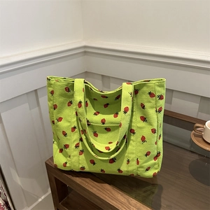 Green corduroy tote bag with strawberry print and dual handles for daily use