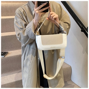 Dettaglio della borsa patchwork in pelle bianca e intrecciata con logo dorato e tracolla