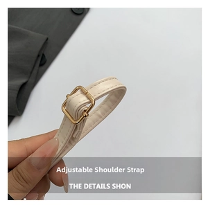 Dettaglio di una tracolla regolabile in pelle beige con raffinata fibbia dorata