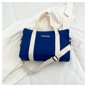 Detailed macro of a navy canvas tote bag with white fashion print and metal hardware