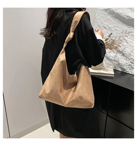 Détail du sac cabas en daim camel montrant la bandoulière nouée et la texture souple