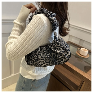 Gros plan de la poignée plissée et du tissu léopard texturé du sac fourre-tout
