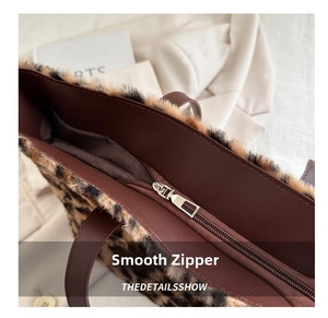 Close-up of smooth silver zipper closure on leopard print faux fur tote bag with brown leather trim