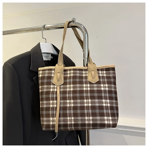 Detailed close-up of brown checkered tote bag with cream leather straps on a hanger