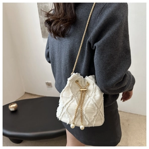 Detail of cream quilted bucket bag with gold chain strap and decorative pearls