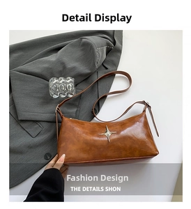 Detail of silver star ornament on brown textured leather shoulder bag with adjustable strap