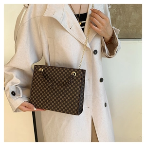 Detail of a vintage crossbody bag with gold chain strap on a trench coat model