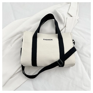 Detail of canvas tote bag showing black fashion text and adjustable shoulder strap hooks