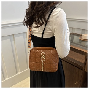 Détail du sac bandoulière matelassé marron foncé avec logo doré et sangle colorée