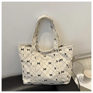 Detail of cream corduroy tote bag with black bow patterns on a modern sofa