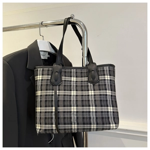 Detail shot of the vintage plaid tote bag with black leather handles and reinforced stitching