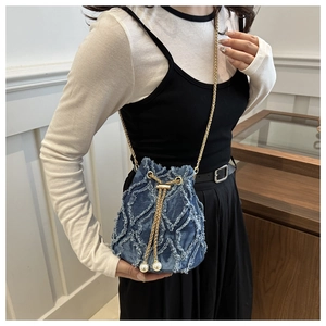 Details der Distressed-Denim-Struktur und Perlenakzente der gesteppten Bucket Bag