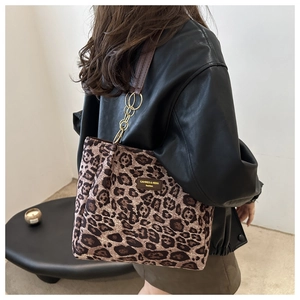Detail view of fashion leopard print tote bag with brown leather strap and gold chain link