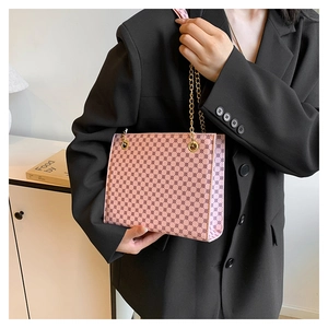 Detail of pink geometric dot pattern crossbody bag with golden chain strap on model