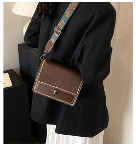 Dettaglio borsa a tracolla marrone vintage con cinturino jacquard e chiusura in metallo