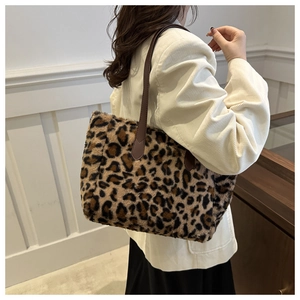 Detail view of leopard print plush tote bag with brown leather straps and metal rivets