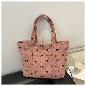 Detailed close-up of pink corduroy tote bag with bow pattern and external front pocket
