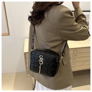 Détail du sac bandoulière matelassé noir avec logo S doré et large bandoulière imprimée