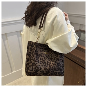 Detail view of leopard print tote bag with brown leather strap and gold chain accent