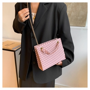 Detail of pink monogram crossbody bag with gold chain strap worn with black blazer