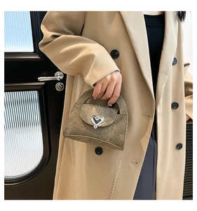 Detail of olive brown retro crossbody bag with large silver heart buckle and chain strap