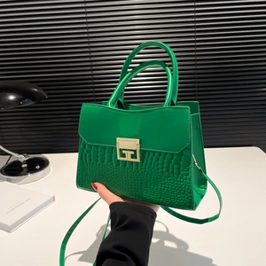 Green faux-crocodile textured handbag with golden hardware and adjustable shoulder strap