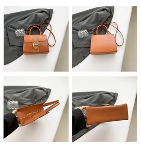 Detail view of orange-brown tote bag featuring crocodile pattern and gold buckle hardware