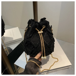 Details einer schwarzen Denim-Beuteltasche mit Steppmuster, Goldkette und Perlenakzent