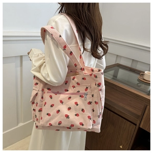 Detailed close-up of pink corduroy tote bag with strawberry prints and metal zipper pocket