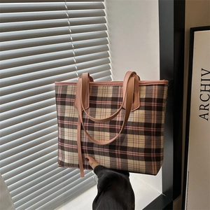 Pink plaid canvas tote bag with leather handles in a modern minimalist setting