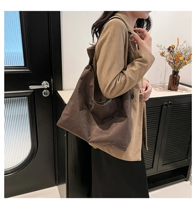 Détail macro du sac cabas en daim marron foncé doté d'une bandoulière large minimaliste