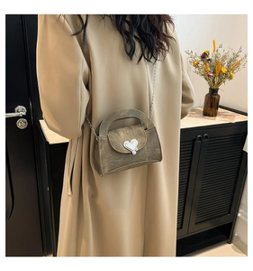 Close-up of vintage brown crossbody bag with silver heart buckle and chain strap on model