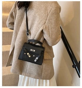 Detailed view of black textured leather bag with metallic clasp and side zipper trim