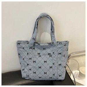 Detail of light blue corduroy tote bag with black bow pattern and diamond quilting texture