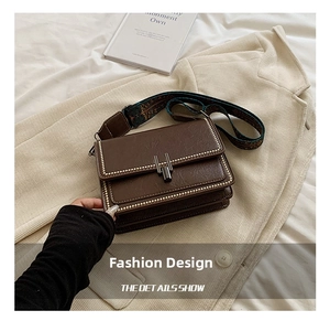 Detail of vintage brown crossbody bag with metal rivets and ethnic pattern strap