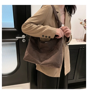 Détail du sac cabas en daim marron foncé avec bandoulière nouée et texture de cuir mat