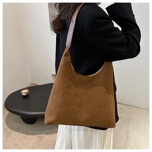 Brown suede half-moon shoulder bag shown from a side-back view on a model