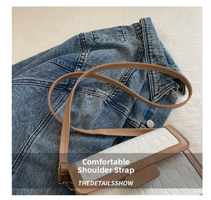 Details der weißen Handtasche mit Krokodilprägung und braunem Rand auf Jeansjacke