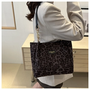 Detail of leopard print tote bag with metal chain strap worn on a gray blazer
